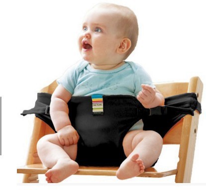 Baby sitting in a wooden chair with a black seat cover and safety belt.