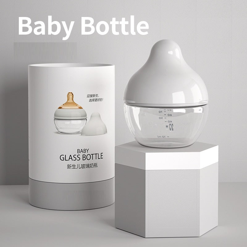 Glass baby bottle with packaging on a gray background