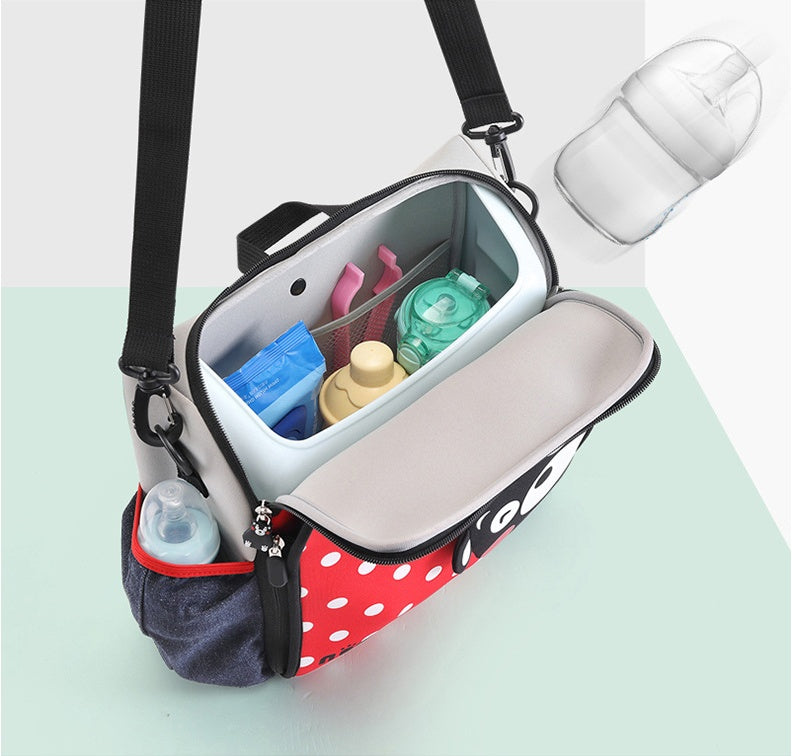 Multifunctional bag with a polka dot design containing baby bottles on a light green background