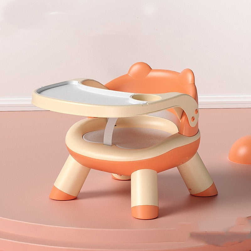 Children's stool with a tray in orange and beige on a pink background