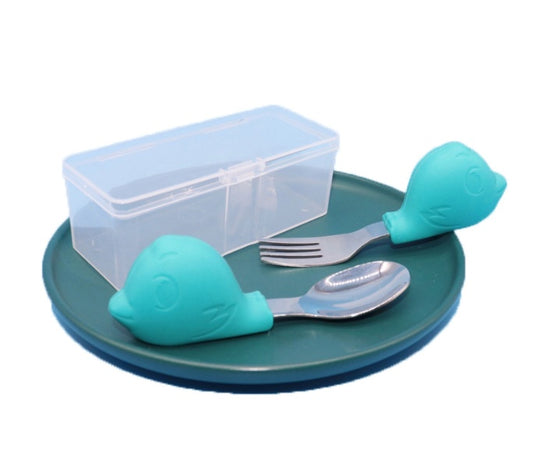 Children's tableware set with fish-shaped cutlery holder, plate, fork, and spoon on a white background.