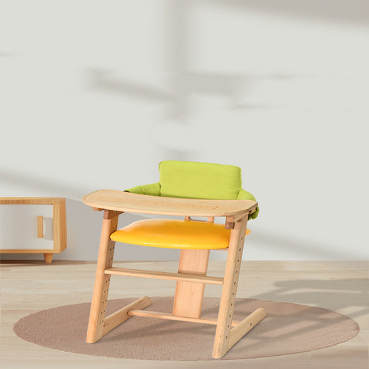 Children's high chair with green cushion and orange seat on a light wooden frame, placed on a beige rug.