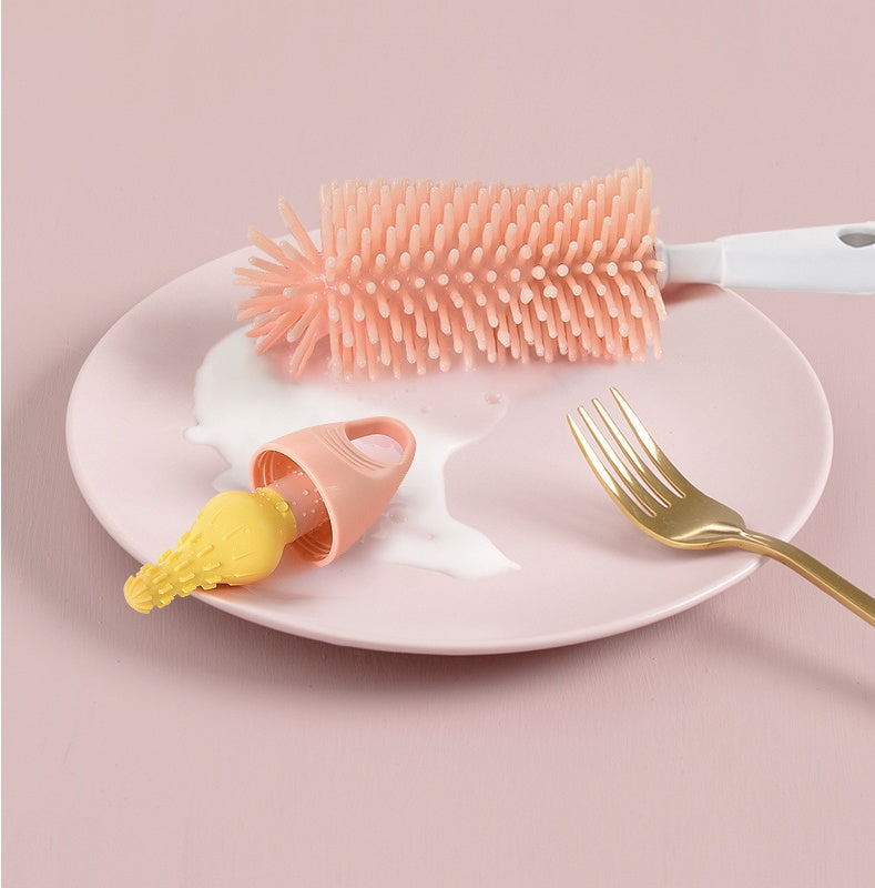 Pink bottle brush, yellow bottle cap, and gold fork on a white plate with pink background