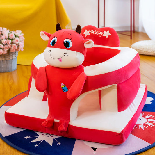 Red and white cow-shaped cushion on a wooden floor with a yellow rug and flowers in the background.