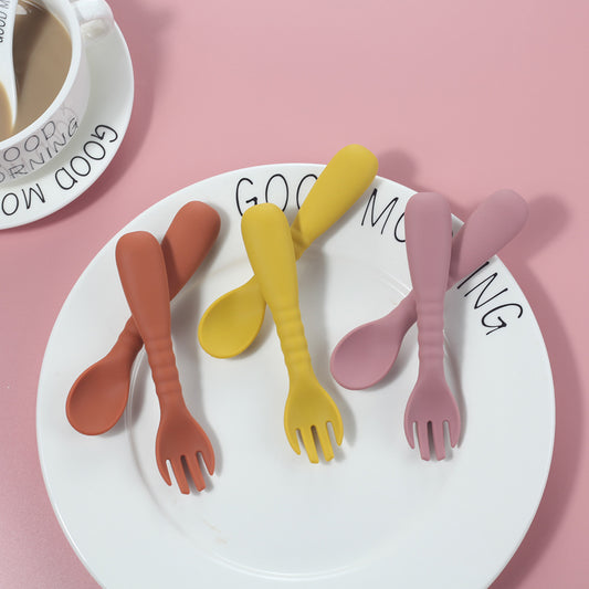 Colorful plastic forks on a plate with 'GOOD MORNING' text, against a pink background.