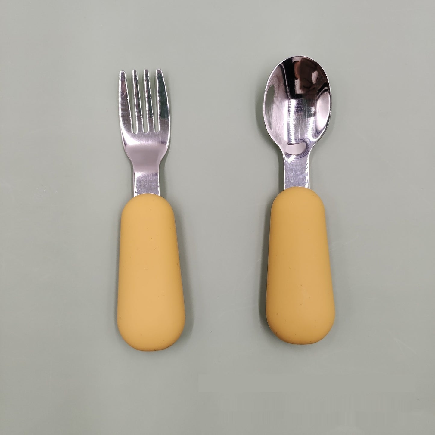 Fork and spoon set with yellow handles on a gray background