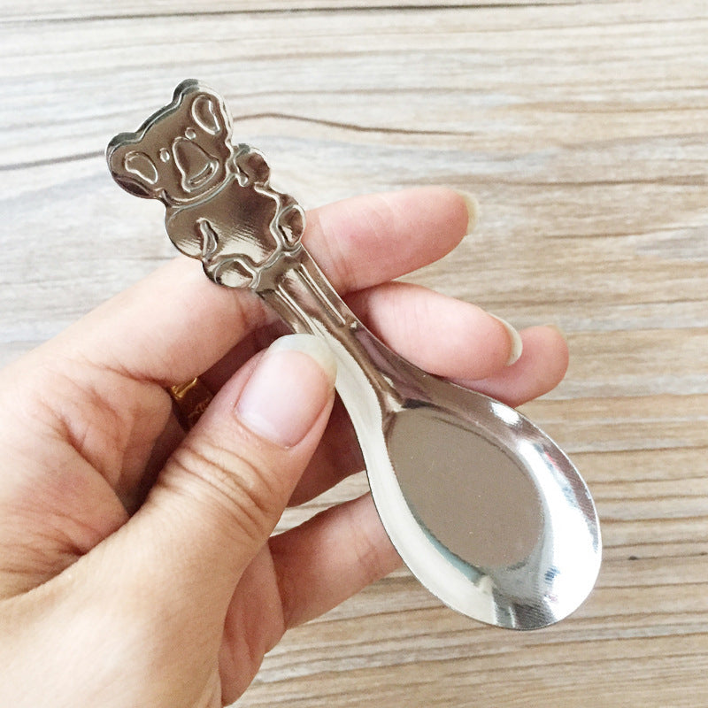 Hand holding a decorative silver spoon against a wooden background