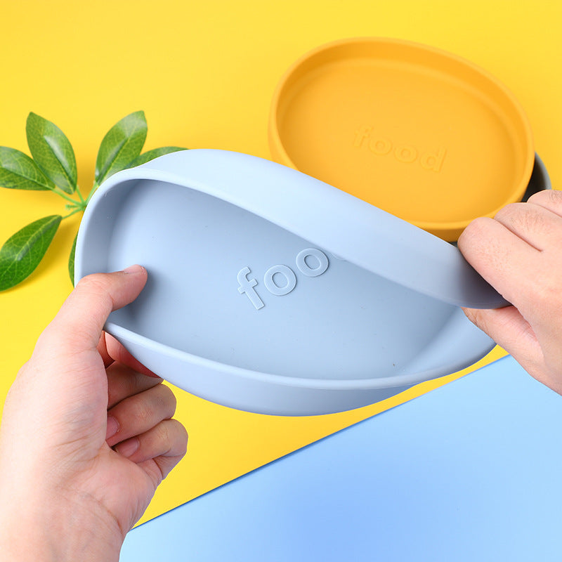 Blue silicone scoop held by a hand with a yellow plate in the background