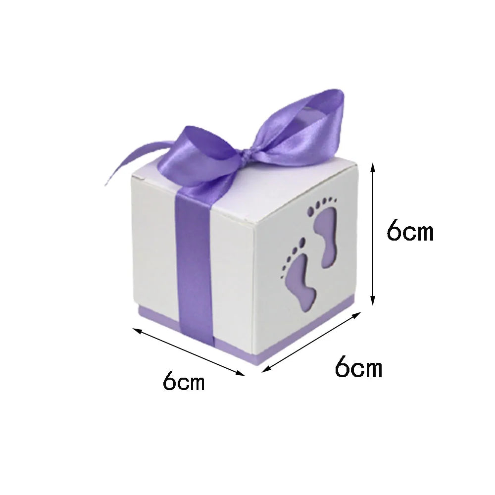 White cube-shaped box with purple ribbon and footprints, dimensions indicated.