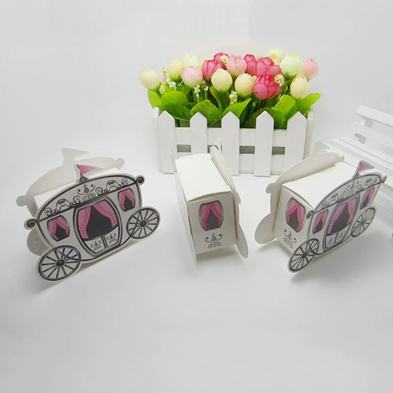 Three paper carriages with pink interiors on a white background, with a small white picket fence and flowers in the background.