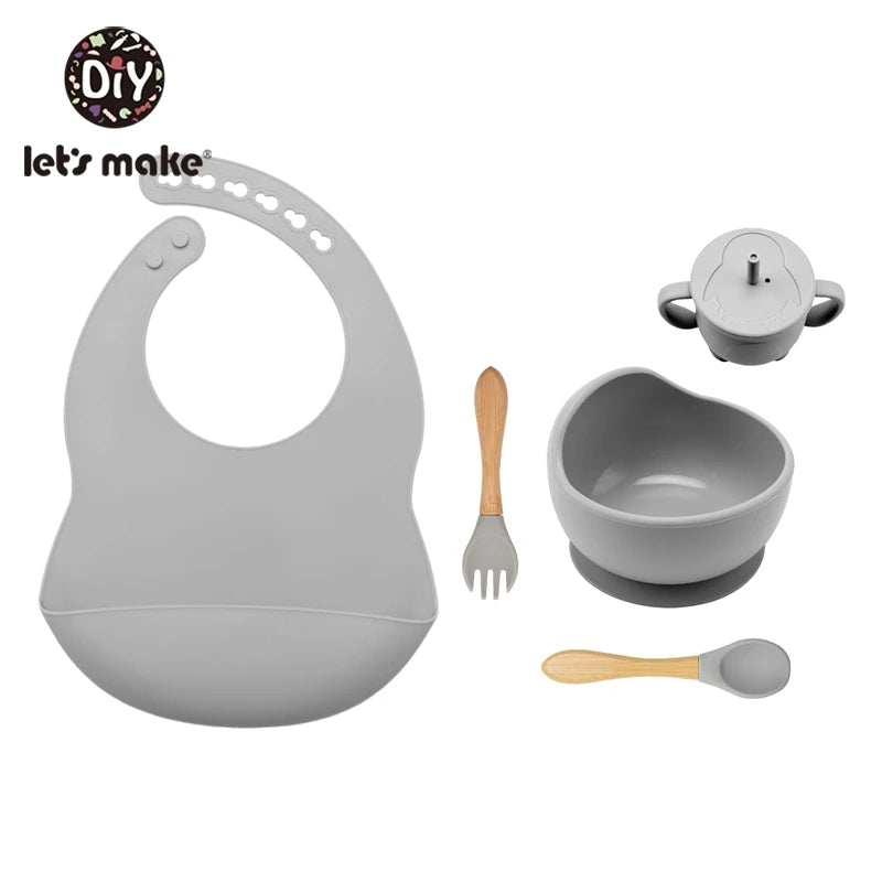 Baby feeding set with bib, bowl, spoon, and fork on a white background