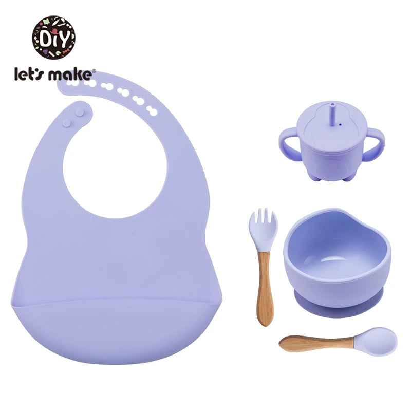 Purple baby feeding set with bib, cup, bowl, fork, and spoon on a white background.