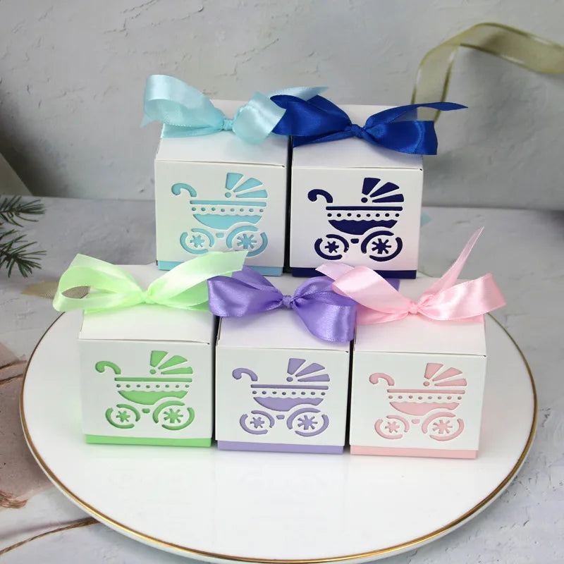 Small boxes with baby carriage design and colorful ribbons on a white surface.
