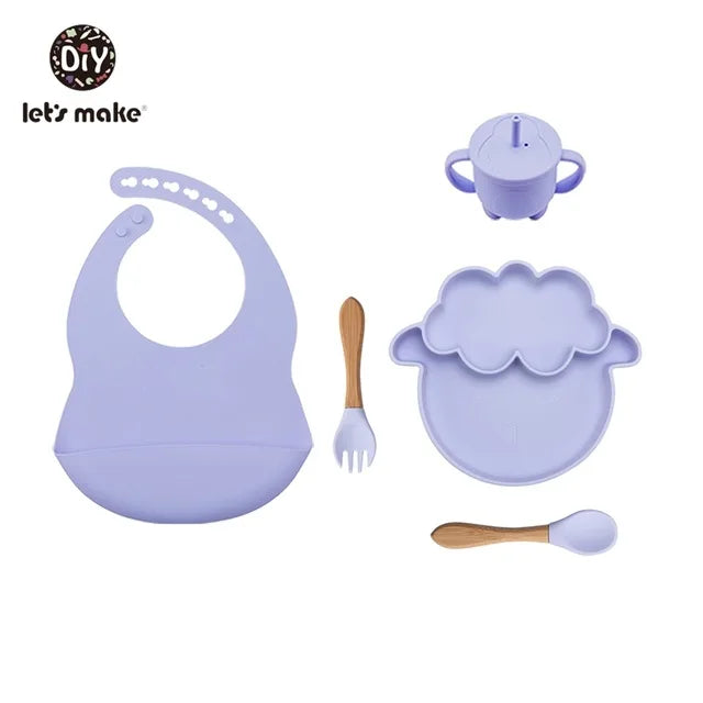 Purple baby dining set with bib, plate, cup, and utensils on a white background