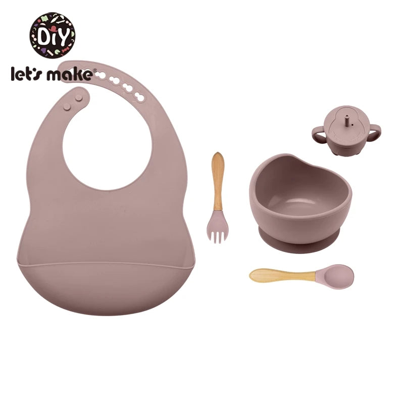 Baby feeding set with bib, bowl, spoon, and fork on a white background