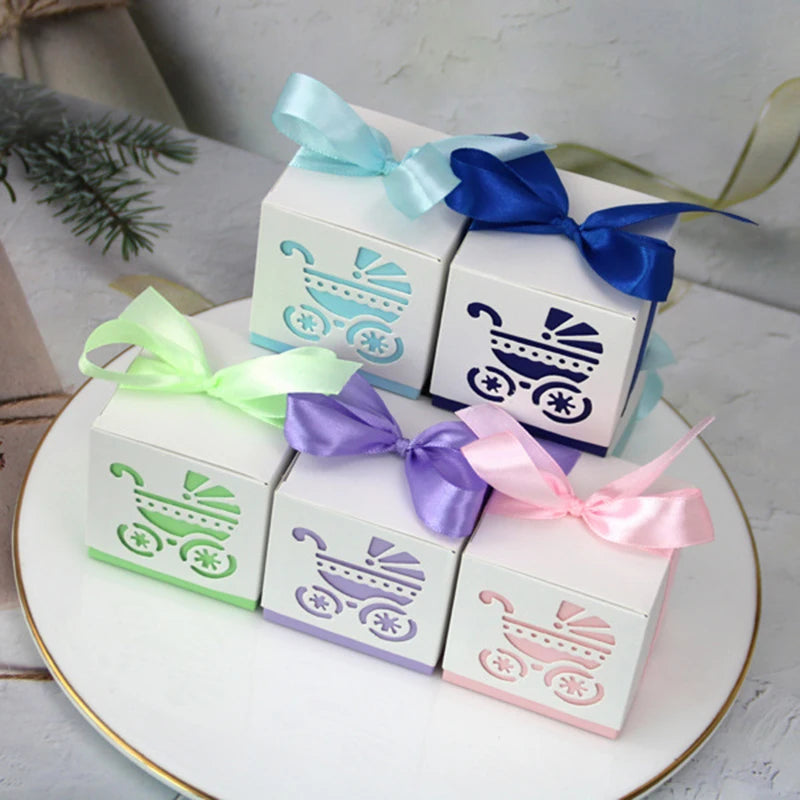 Four decorative boxes with baby stroller designs and colorful ribbons on a white surface.