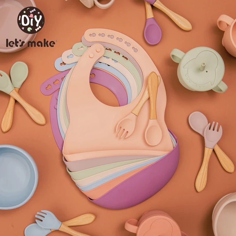 Colorful baby bib and utensils set on a brown background with 'let's make' branding.