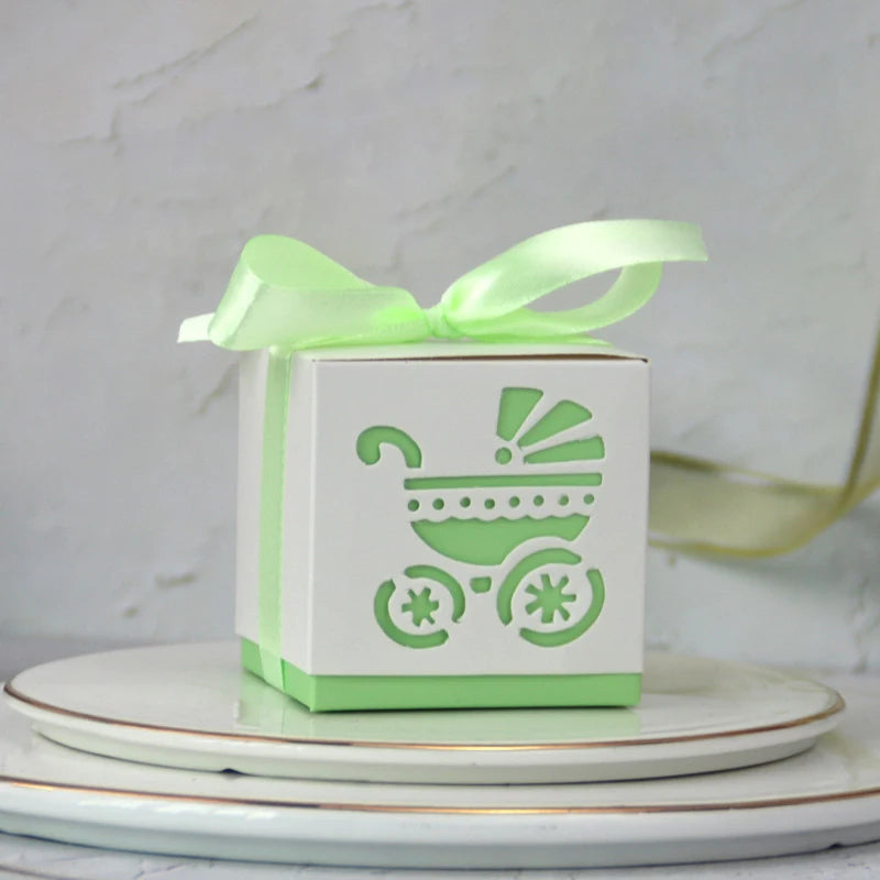 Gift box with baby carriage design and green ribbon on a white surface