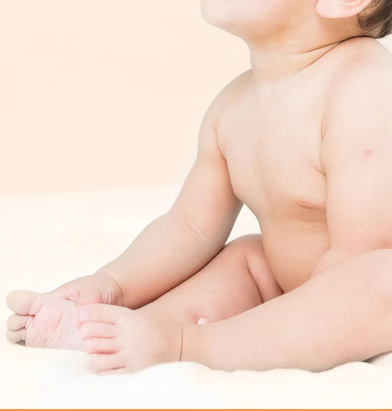 Baby sitting on a white surface with a plain background