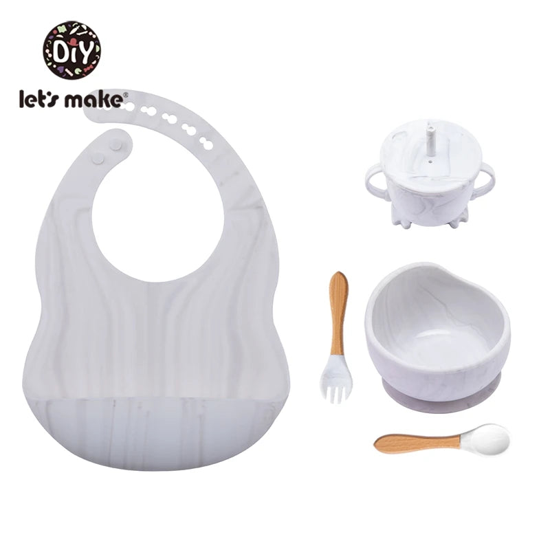 Baby feeding set with bib, bowl, spoon, and fork on a white background