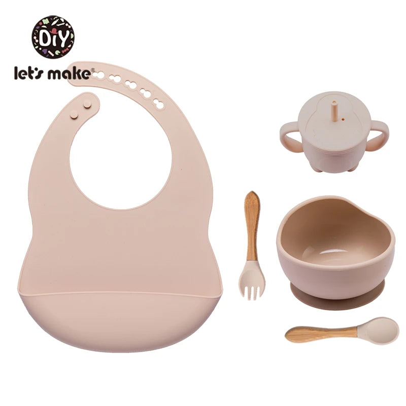 Baby feeding set with bib, cup, bowl, spoon, and fork on a white background