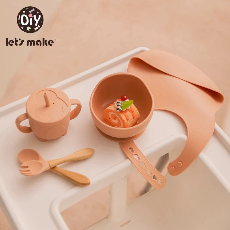 Children's silicone dining set with bowl, cup, and utensils on a white tray.
