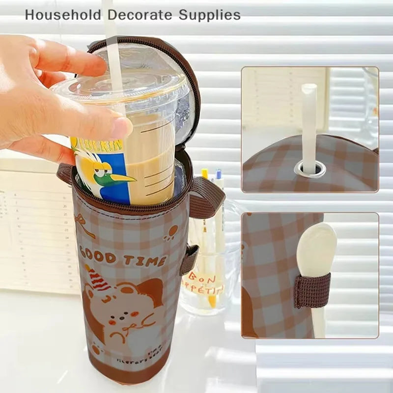 Hand holding a tumbler with a cartoon design, surrounded by additional tumblers and a spoon.