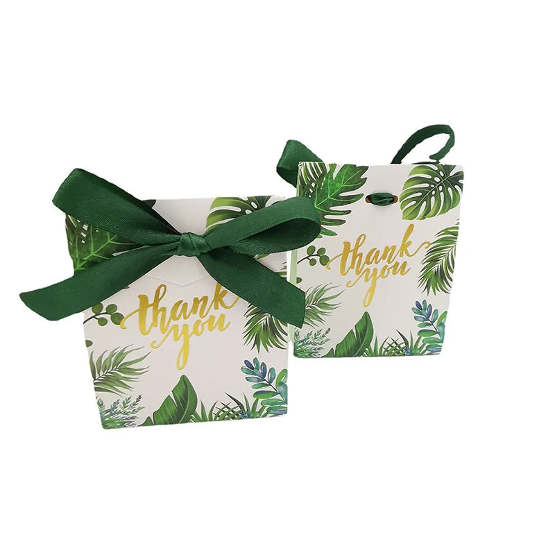 Two small pouches with tropical leaf pattern and 'thank you' text, tied with green ribbons on a white background.