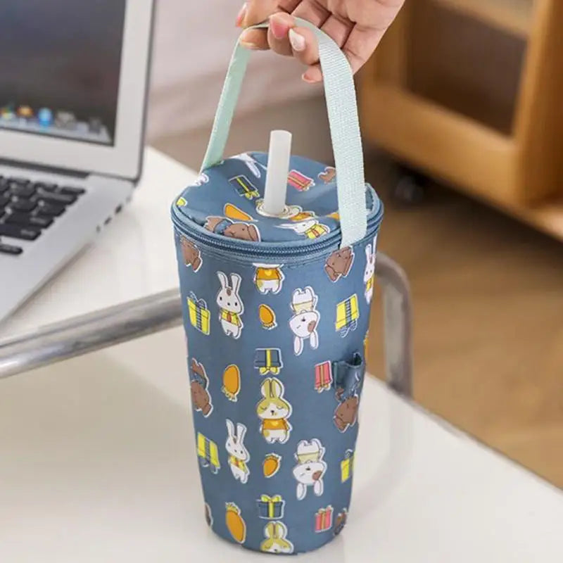 Blue cylindrical tumbler with cartoon characters on a desk next to a laptop