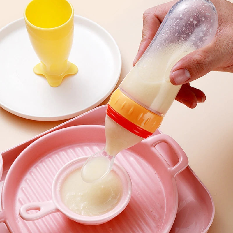 Person using a baby bottle to feed from a pink bowl with a yellow cup in the background.