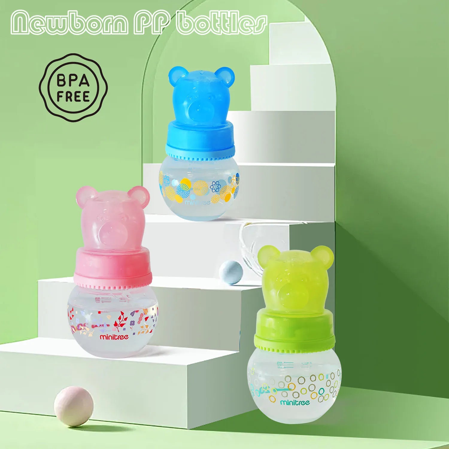 Three colorful baby bottles with bear-shaped tops on a green background, featuring 'BPA FREE' label.