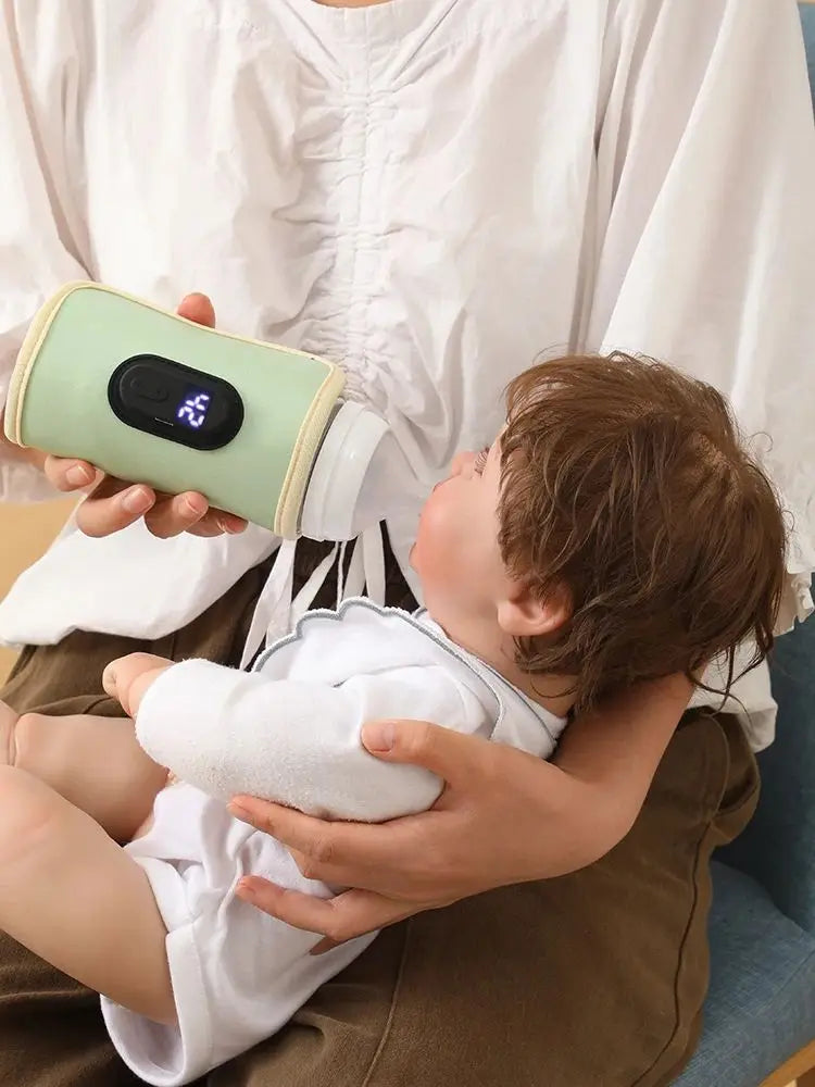 Green portable USB baby milk warmer with digital display, held by a caregiver, ideal for travel. Brand: Nestacular.
