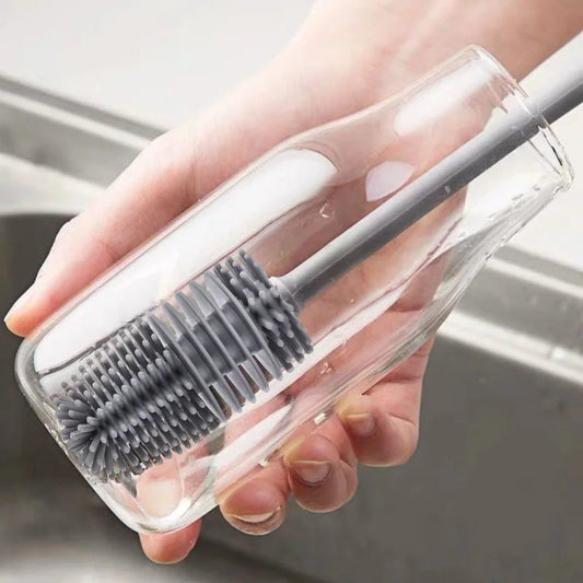 Gray silicone baby bottle brush with a 360-degree rotating head and long handle for easy cleaning, by Nestacular.