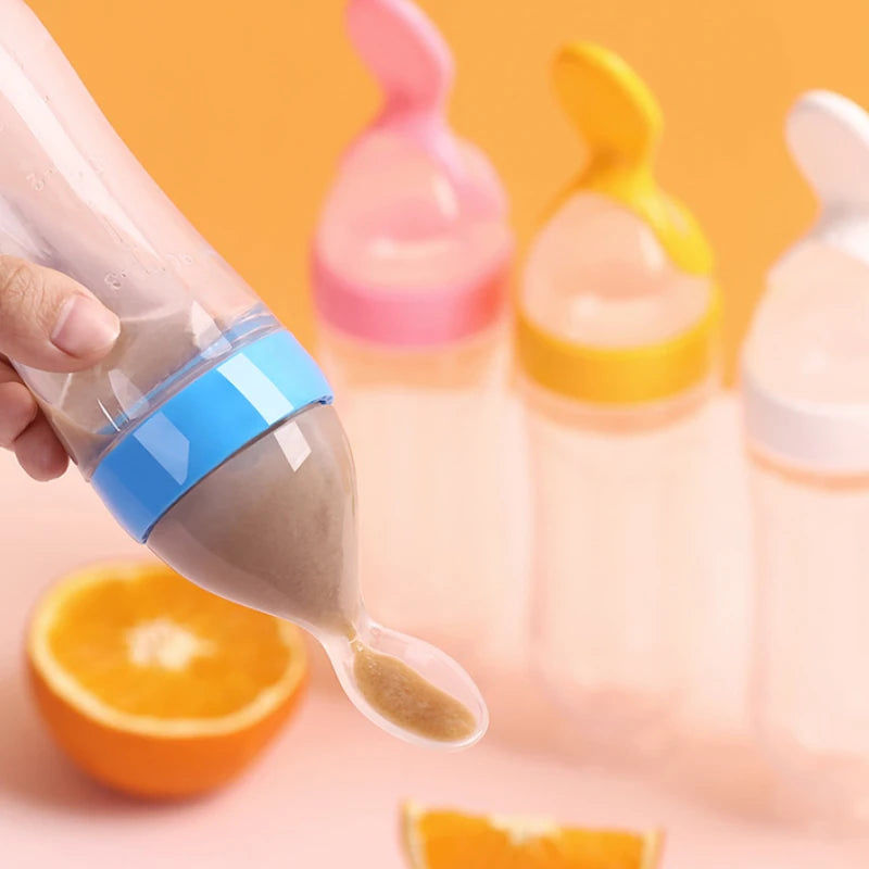 Baby bottle with a spoon being used to scoop out formula, with oranges in the background.