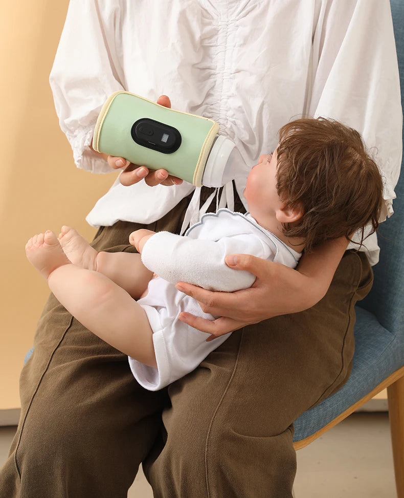 Person holding a baby and a green electronic device on a chair.