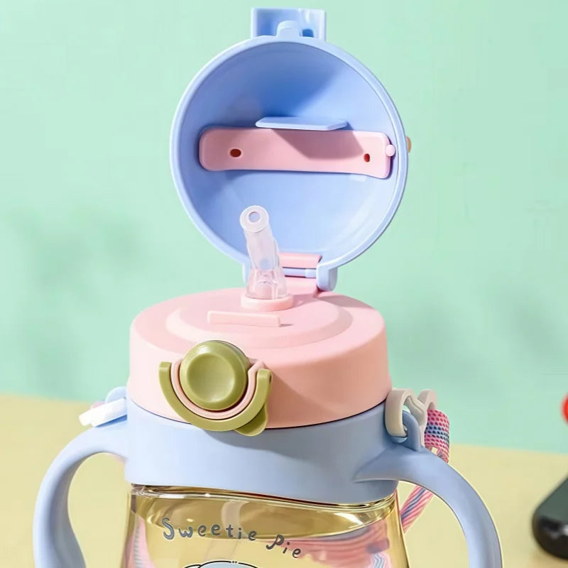 Children's sippy cup with pink and blue lid on a light green background