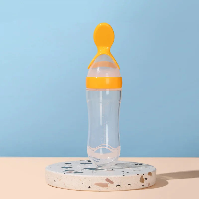 Clear baby bottle with orange cap on a terrazzo coaster against a blue background
