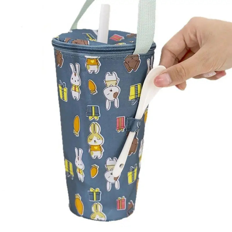 Blue insulated cup with cartoon designs held by a hand against a white background