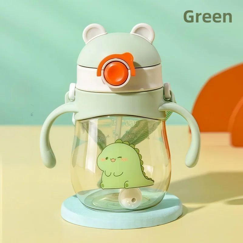 Children's green dinosaur-themed water bottle with handle and straw on a yellow and light blue background.