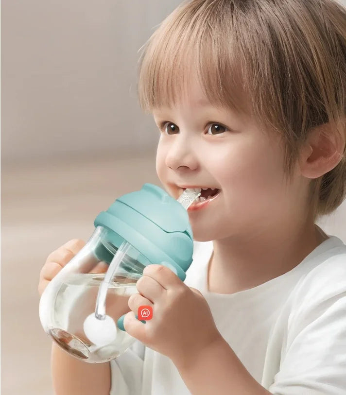 Child holding a green sippy cup with a smile on their face