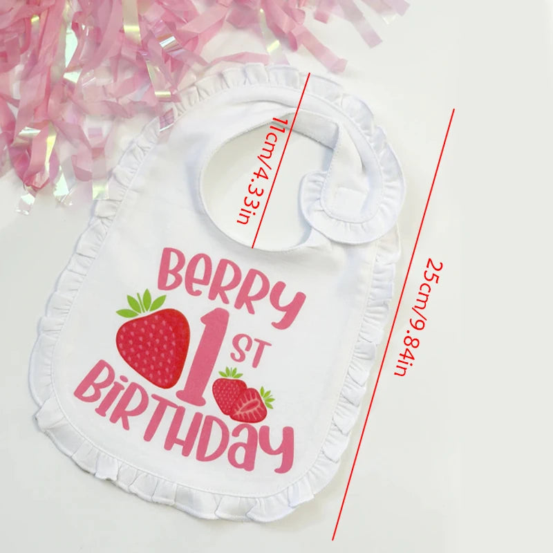 White bib with 'Berry 1st Birthday' text and strawberry graphics, with measurements indicated.