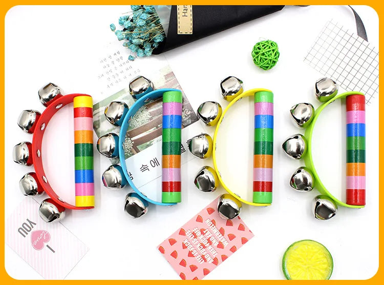 Colorful jingle bells on a white surface with a black book and green decorative item.