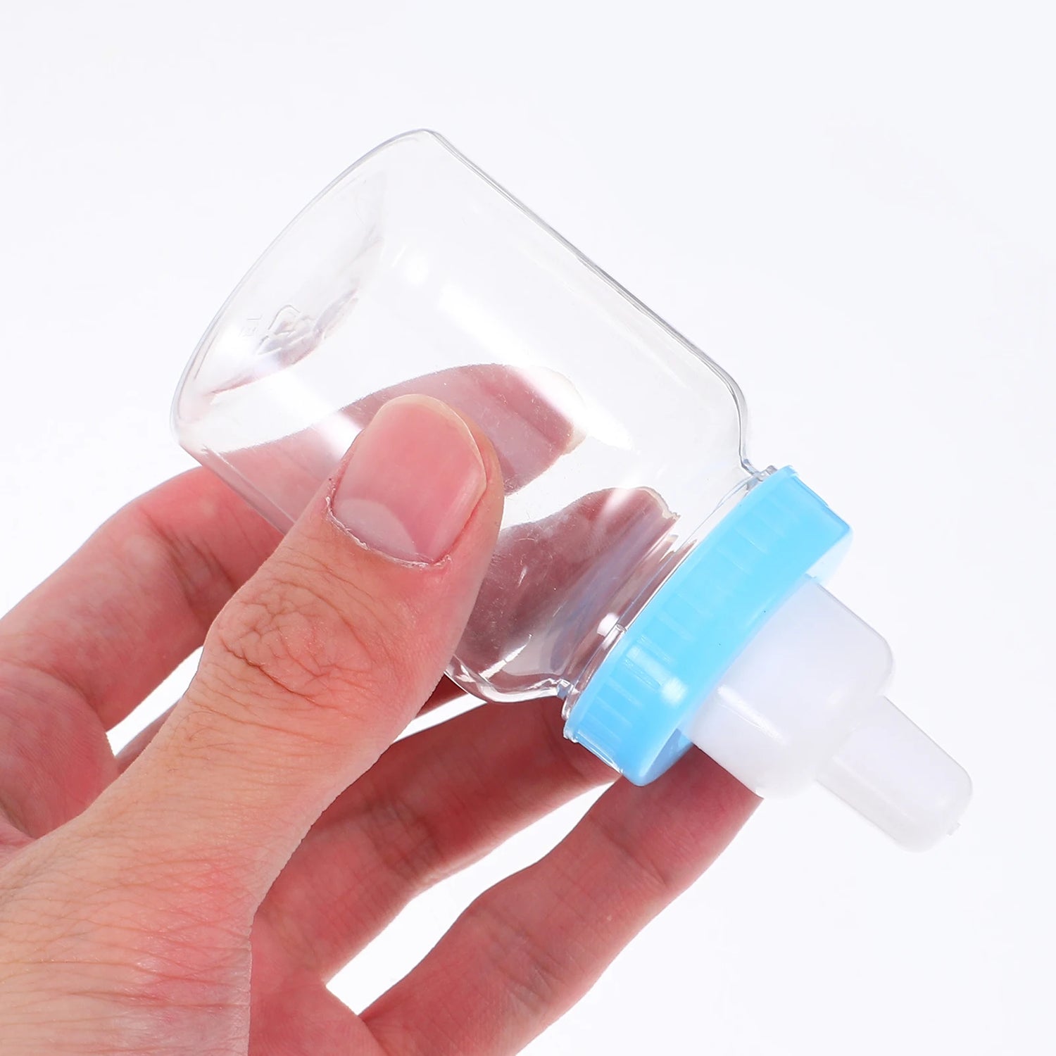 Clear plastic device with blue cap held by a hand on a white background