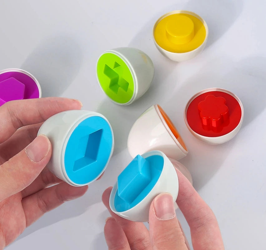 Colorful geometric shape sorting toys with a hand interacting with one of them on a white background.