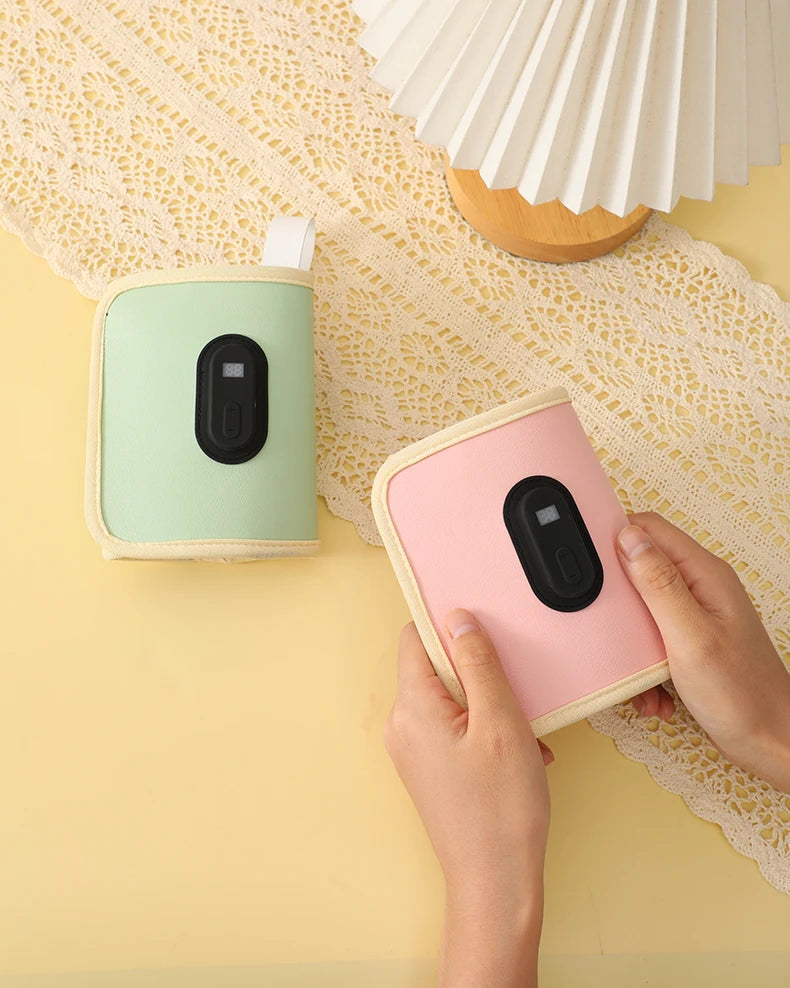 Two small electronic devices, one pink and one green, on a yellow surface with a hand interacting with the pink device.