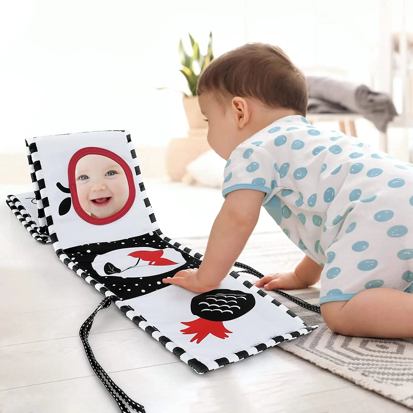Child playing with a baby book on a light wooden floor.