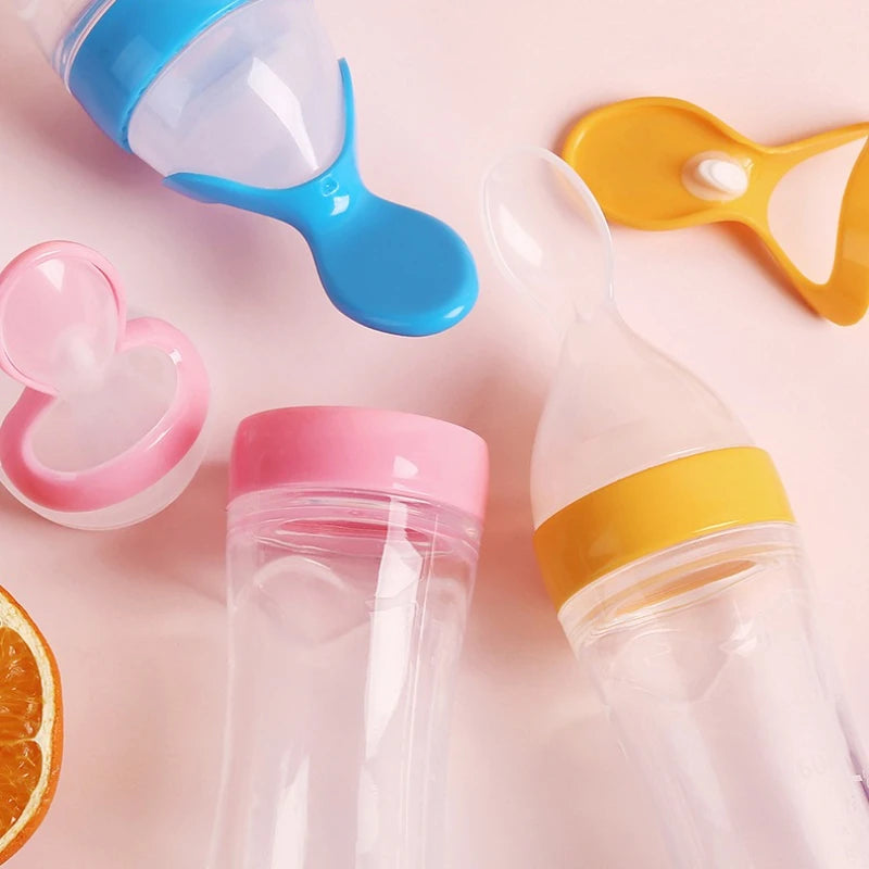 Silicone baby feeding bottles with spoon, round bottom, in pink, yellow, and blue by Nestacular.