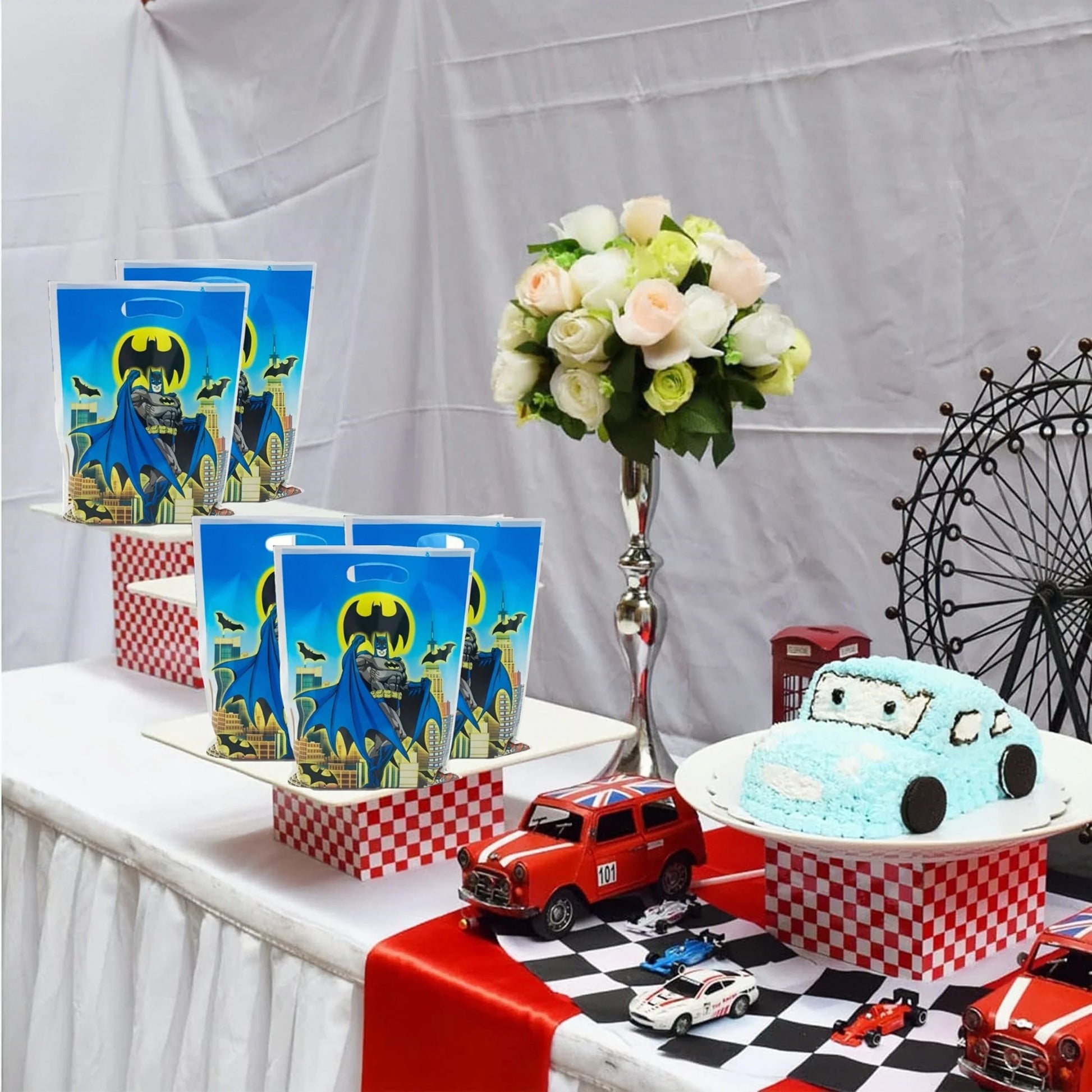 Table setting with Batman-themed decorations, including a cake and tableware, against a white backdrop.