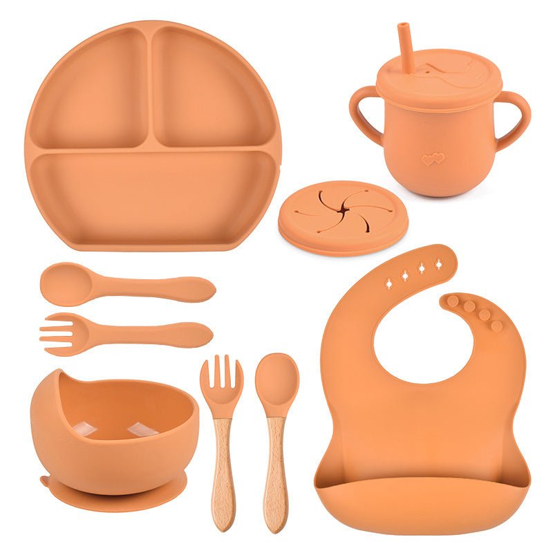 Set of orange silicone dining utensils and accessories on a white background