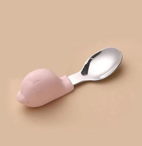 Spoon with pink silicone handle on a beige background